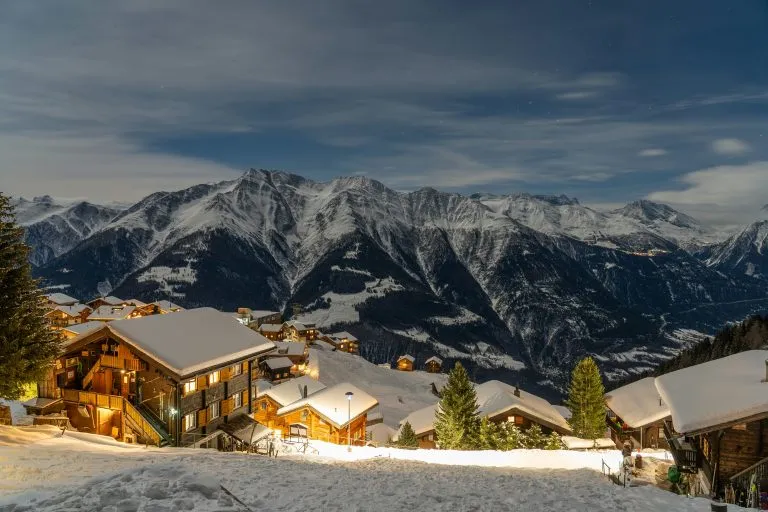 Chalets in a snowy alpine village under mountain peaks