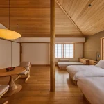 Traditional Japanese guest room at Azuma Farm Koiwai in Iwate Prefecture, Japan, featuring warm wood interiors, low beds, and shoji screens