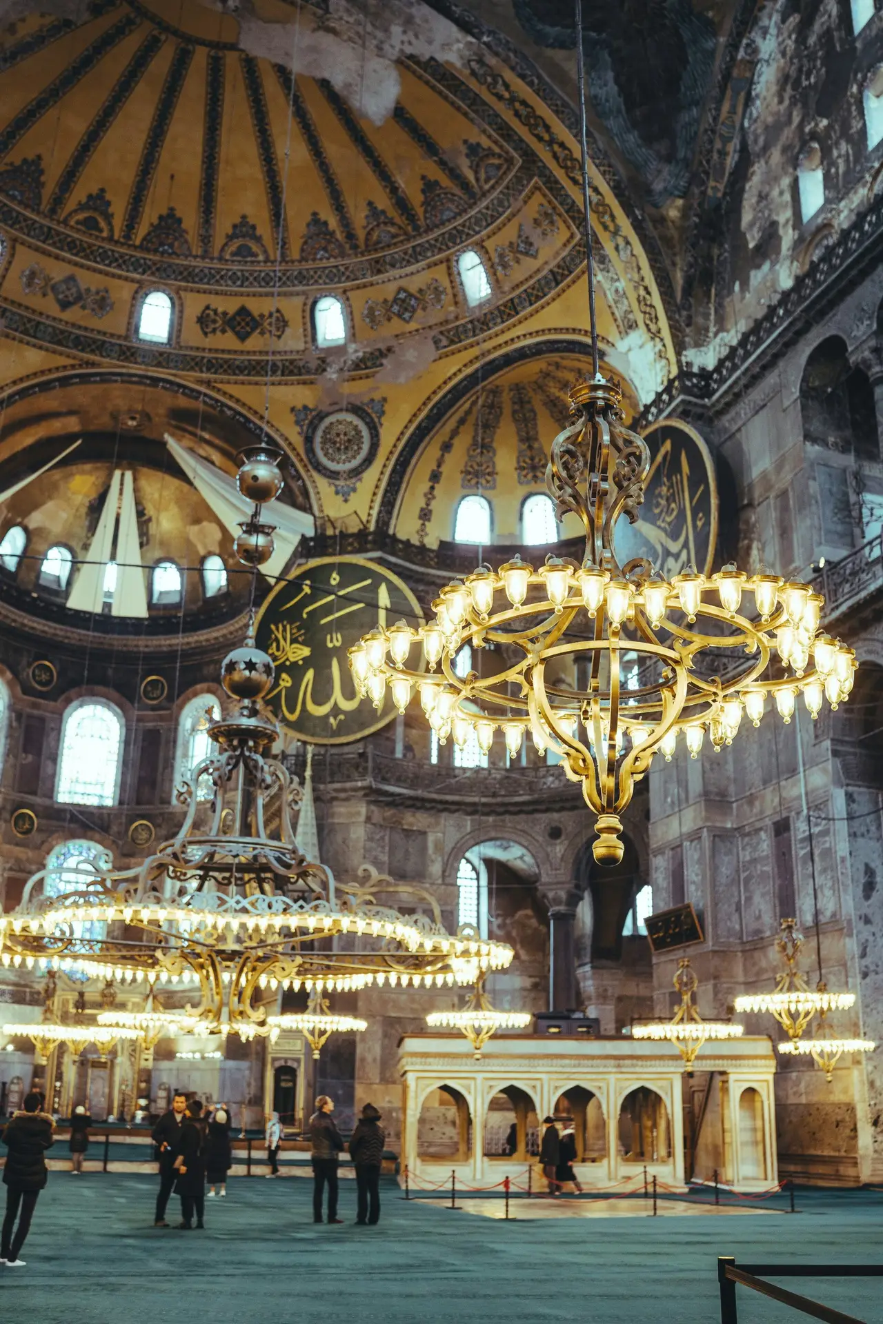 Hagia Sophia interior in Istanbul with golden dome, chandeliers, and Arabic calligraphy, a building that has changed function six times since 537 AD