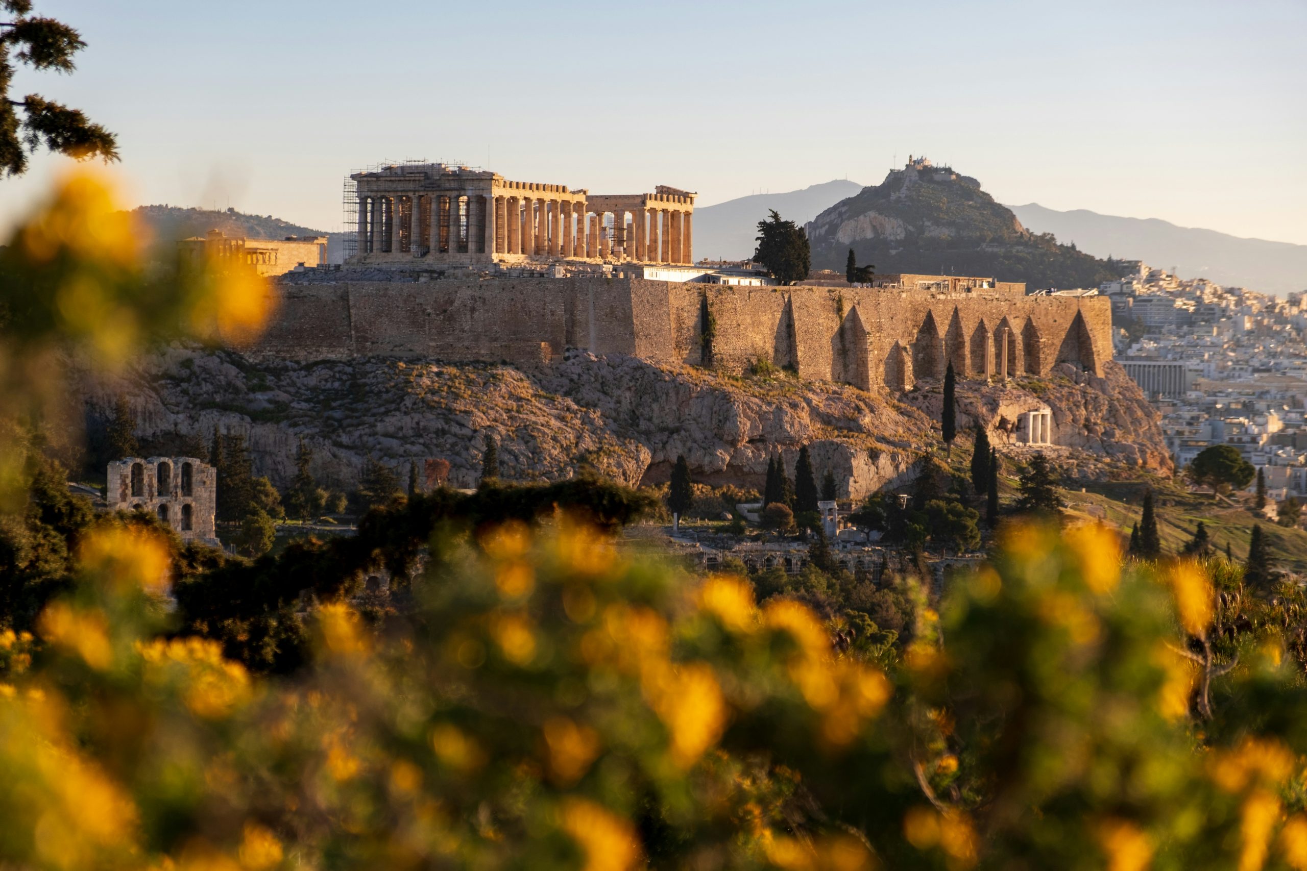 The Acropolis and Parthenon in Athens bathed in golden light with Mount Lycabettus in the background