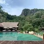 The infinity pool at Cauayan Boutique Private Island with the thatched Horizon Restaurant, white sand beach and Bacuit Bay limestone karsts behind