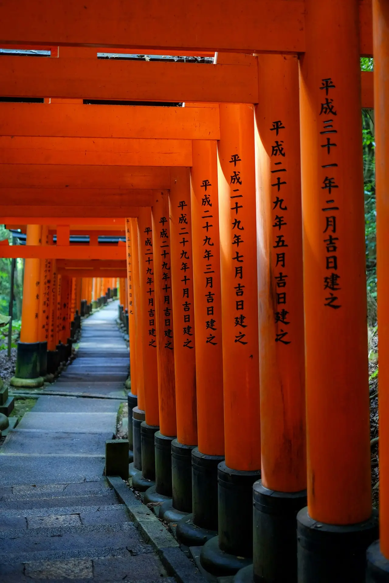 Orange torii gates with Japanese inscriptions at Fushimi Inari shrine in Kyoto, best visited at sunrise or after dark