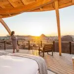 A guest in a robe watches the sunset from the star bed terrace at Onduli Ridge, Damaraland, Namibia