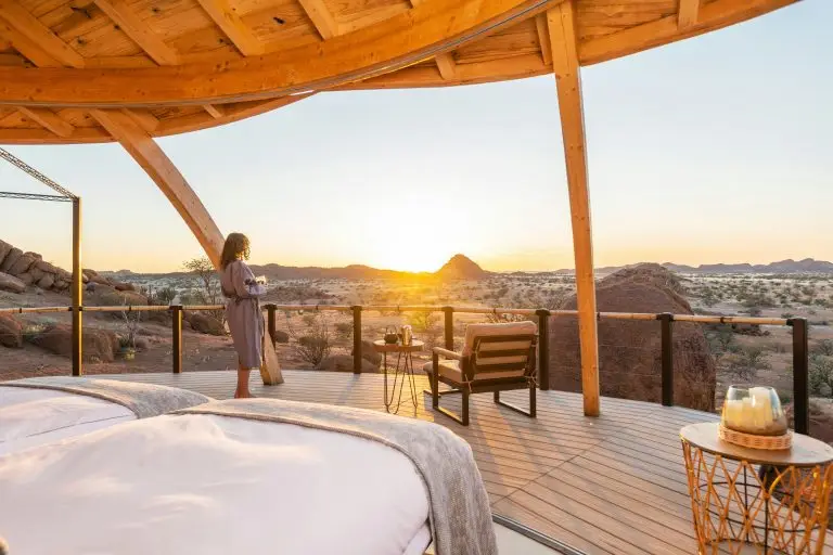 A guest in a robe watches the sunset from the star bed terrace at Onduli Ridge, Damaraland, Namibia