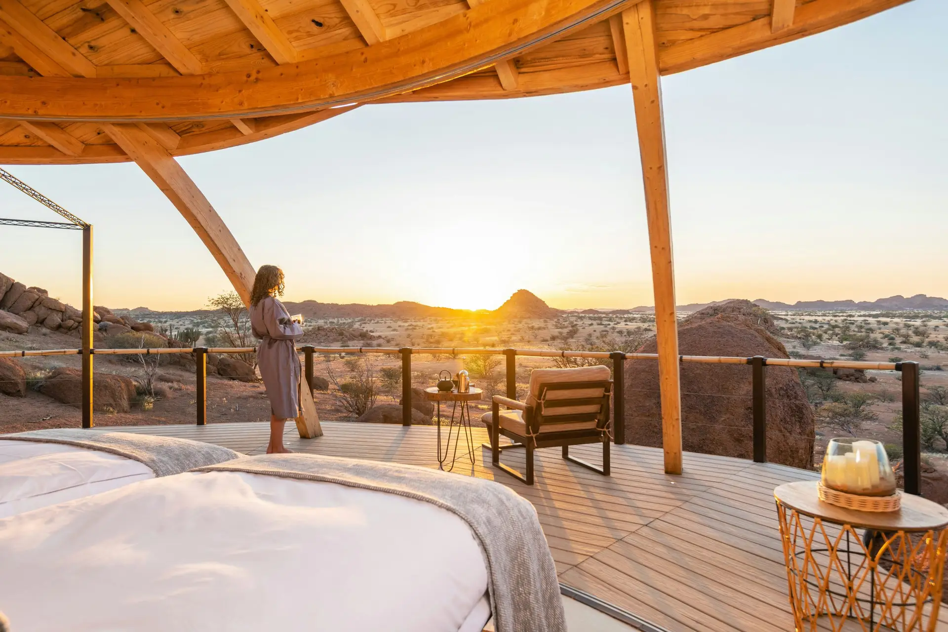 A guest in a robe watches the sunset from the star bed terrace at Onduli Ridge, Damaraland, Namibia