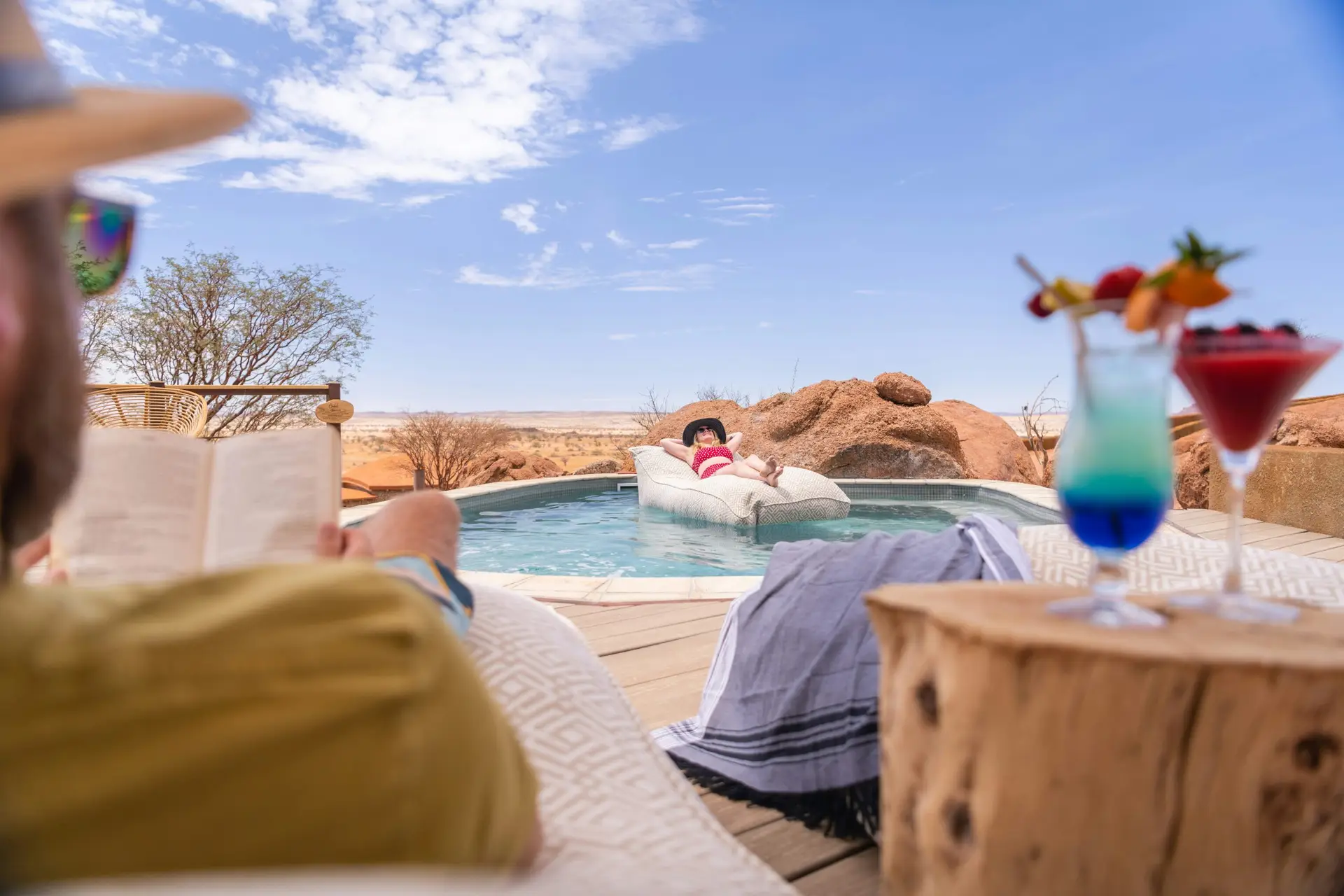  Guests relaxing by the pool at Onduli Ridge with cocktails, a book and bean bag loungers among the granite boulders
