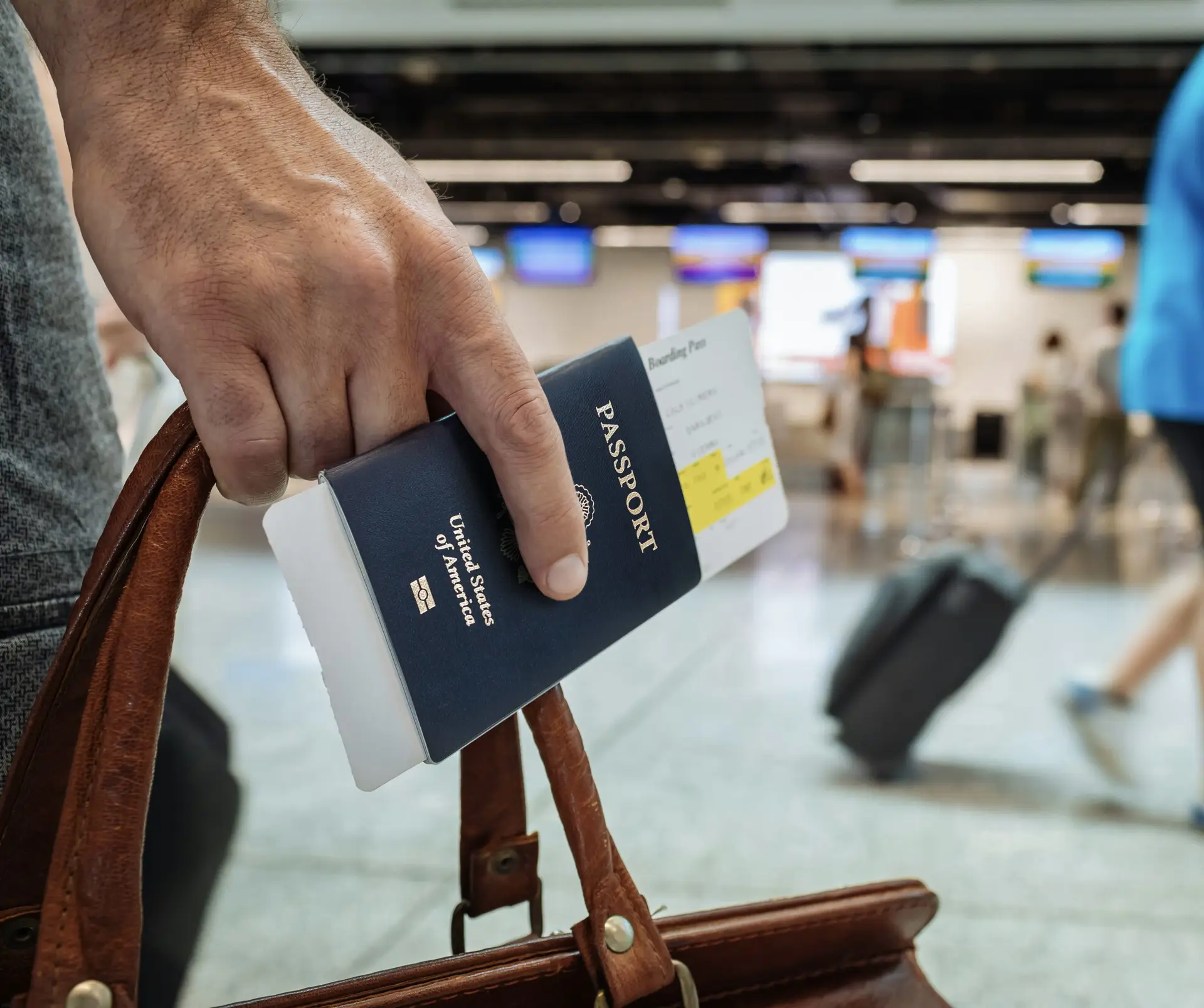 American traveler holding a US passport and boarding pass at an international airport, illustrating the new ETIAS travel authorisation requirement coming to Europe in late 2026