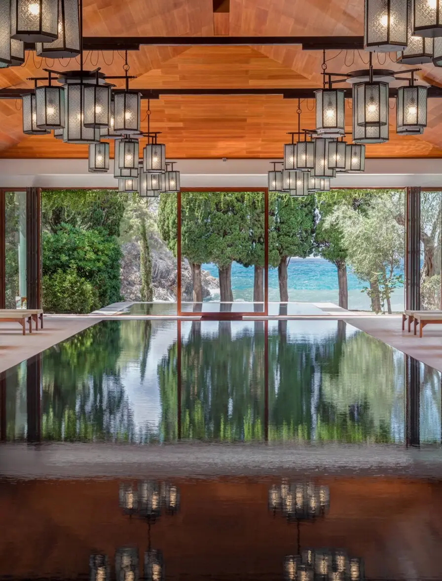 After five years, Aman Sveti Stefan reopens on the Adriatic 1 The 24-meter indoor-outdoor pool at Aman Spa, Sveti Stefan, framed by cedar ceiling, lantern installation, and cypress trees opening to the Adriatic.