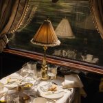 A fringed Art Deco lamp glows beside a half-finished breakfast as the French countryside blurs past a Venice Simplon-Orient-Express window.