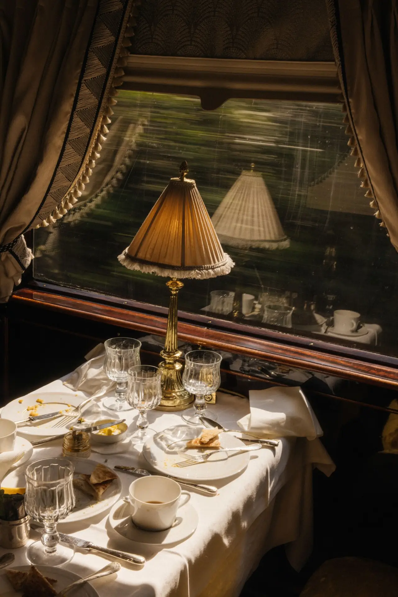 A fringed Art Deco lamp glows beside a half-finished breakfast as the French countryside blurs past a Venice Simplon-Orient-Express window.
