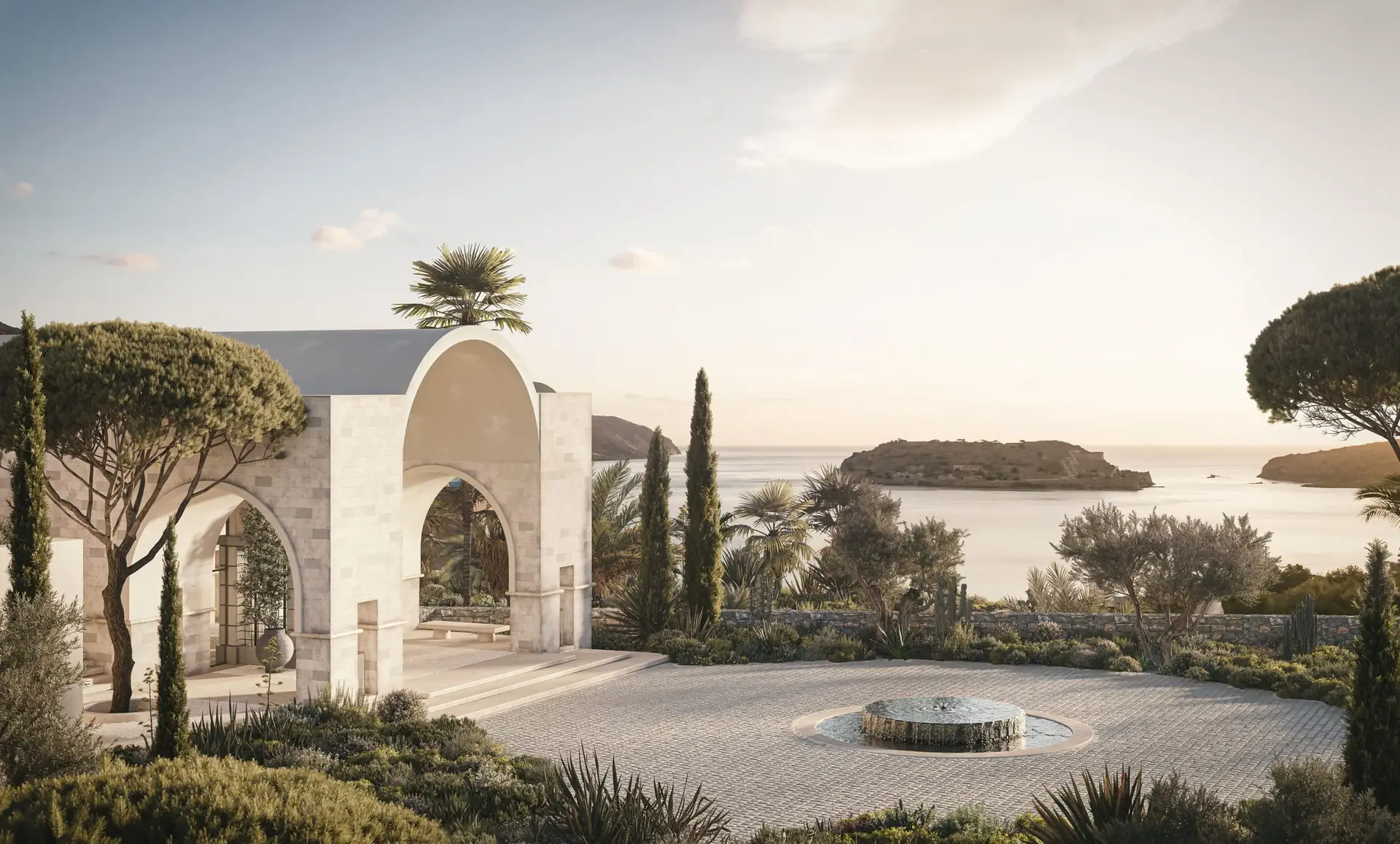 Stone arched pavilion at Rosewood Blue Palace in Elounda, Crete, with Mediterranean gardens and views across Mirabello Bay toward Spinalonga Island 