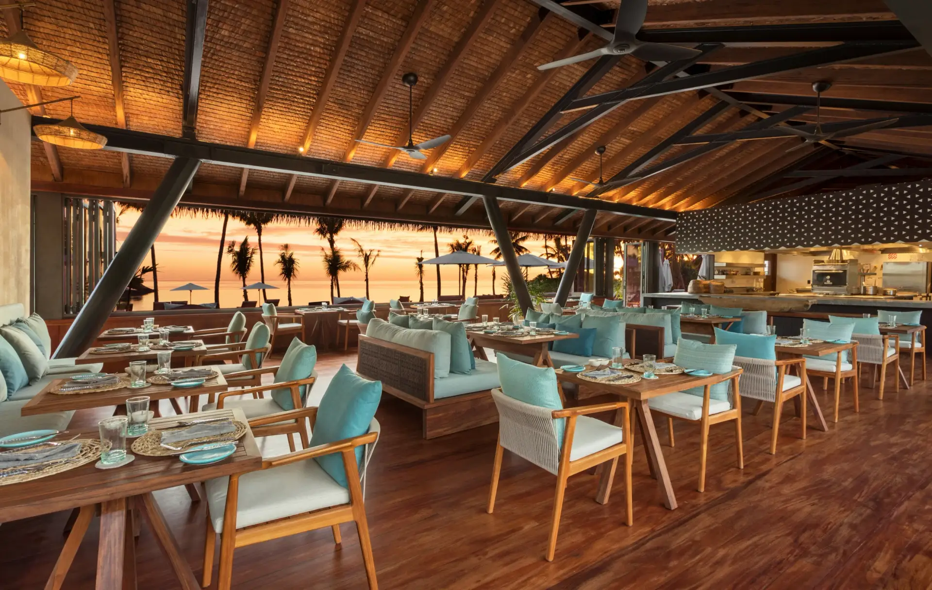 Six Senses Fiji Opens Three Beachfront Residences on Malolo Island 3 Tovolea restaurant at Six Senses Fiji at sunset, with open-sided thatched roof, ocean view and dining setup