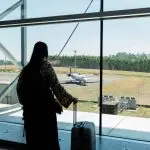 Solo travel destinations 2026: a traveler with luggage waits at an airport gate, capturing the quiet first moments before a solo trip