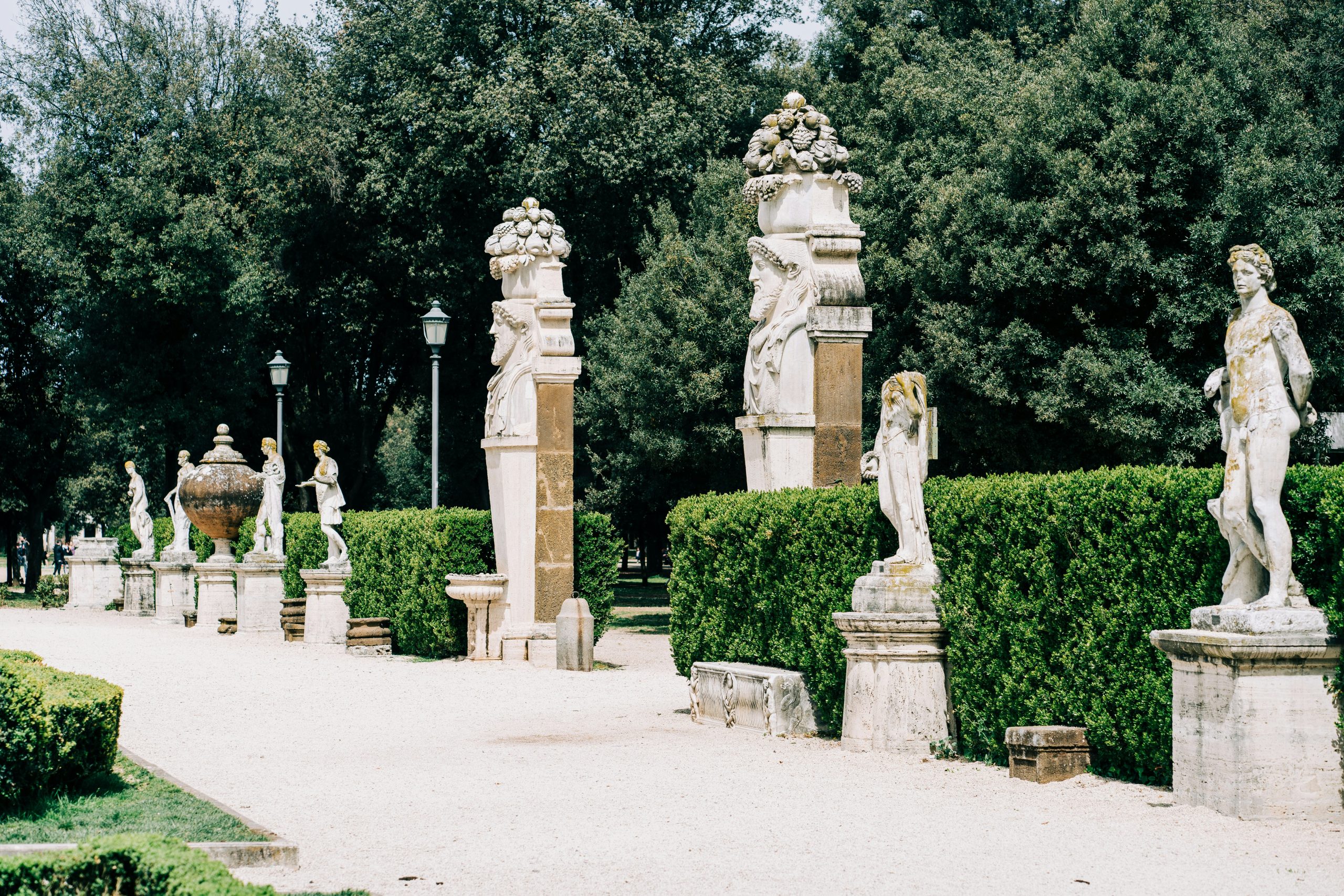 Classical statues and hermae sculptures along the boxwood hedges of Villa Borghese gardens in Rome, the historic park adjacent to Via Veneto and a short walk from Baccarat Hotel Rome 
