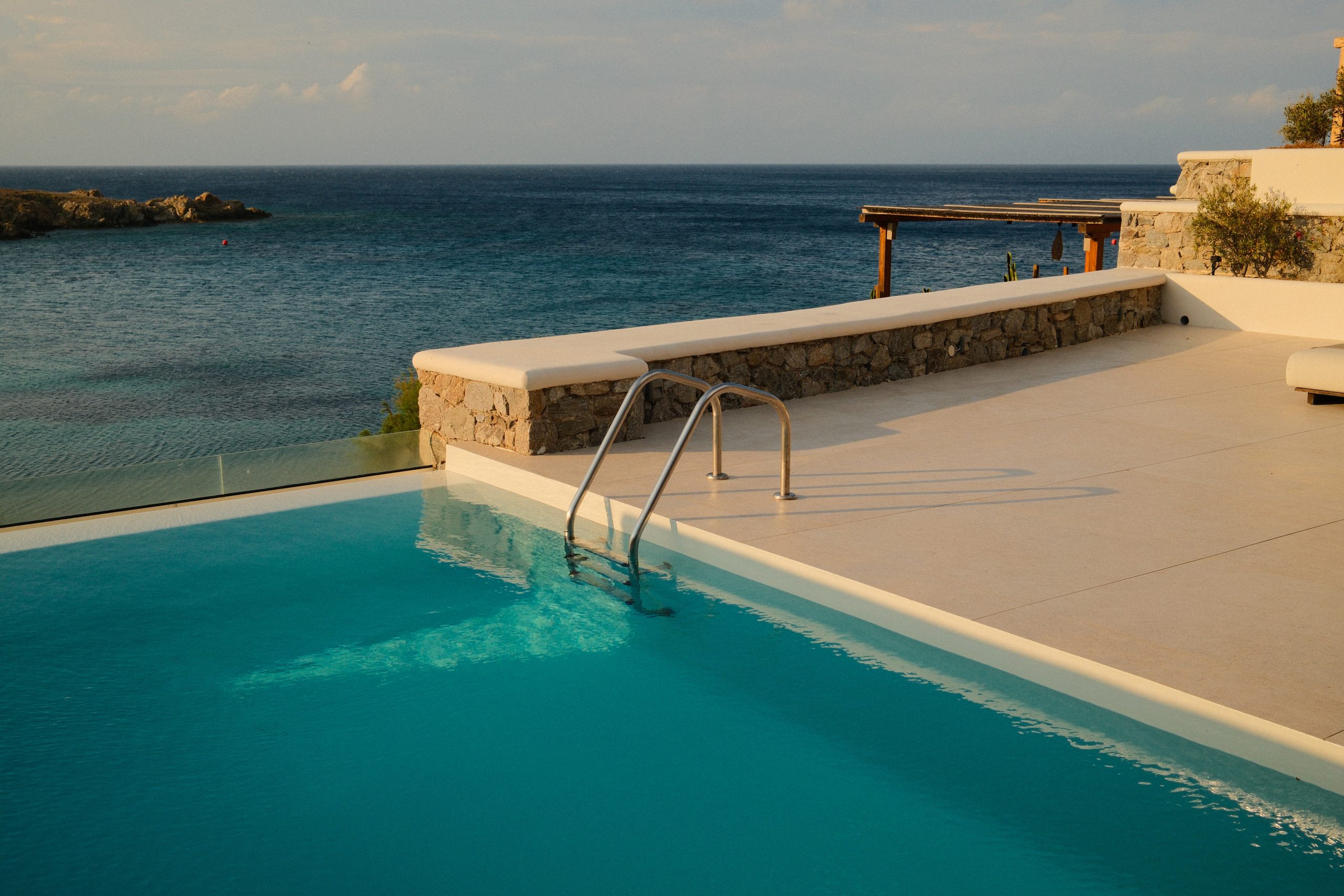 Casa Del Mar Mykonos: A Week on the Quiet Side of the Island 1 Private infinity pool at Casa Del Mar Mykonos meeting the deep blue Aegean at golden hour, with a stone terrace and the rocky coastline beyond