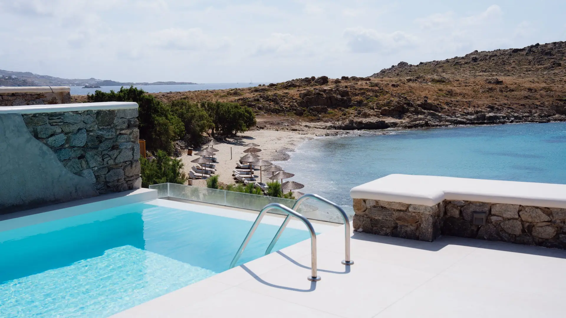 Casa Del Mar Mykonos: A Week on the Quiet Side of the Island 4 Private infinity pool on the terrace of the Royal Beachfront villa at Casa Del Mar Mykonos, overlooking Glyfadi cove with thatched umbrellas and sun loungers on the beach below