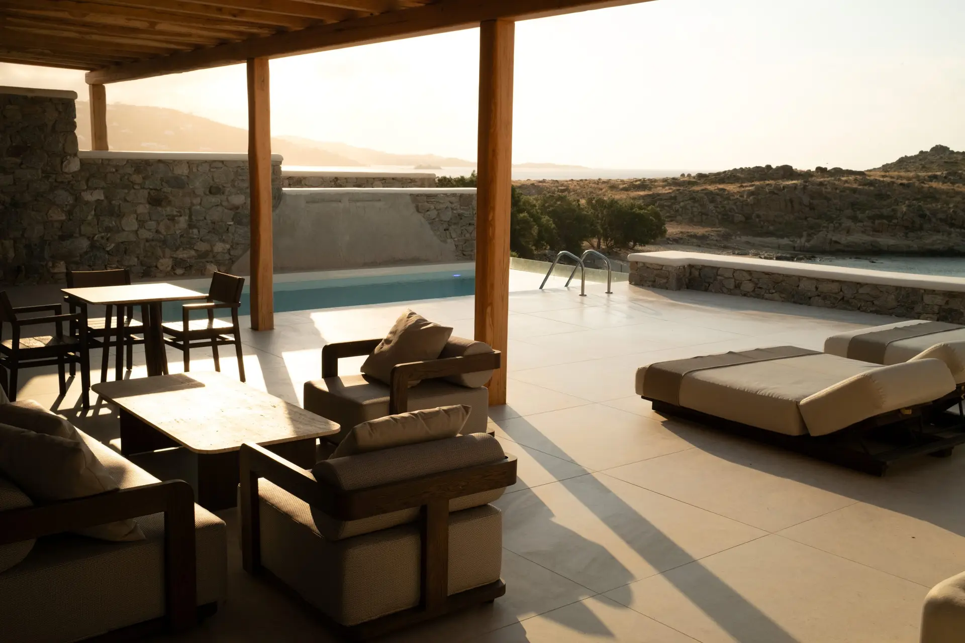 Casa Del Mar Mykonos: A Week on the Quiet Side of the Island 5 Covered terrace of the Royal Beachfront villa at Casa Del Mar Mykonos at golden hour, with lounge seating, a dining table, daybeds, the private infinity pool and the sea beyond