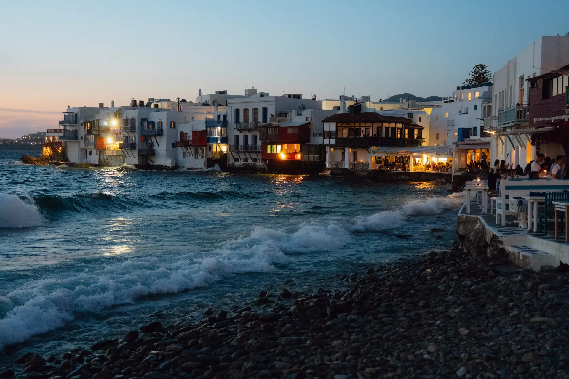 Casa Del Mar Mykonos: A Week on the Quiet Side of the Island 20 Little Venice in Mykonos Town at dusk, with whitewashed houses built right at the water's edge, lit café terraces, and waves breaking against the rocks