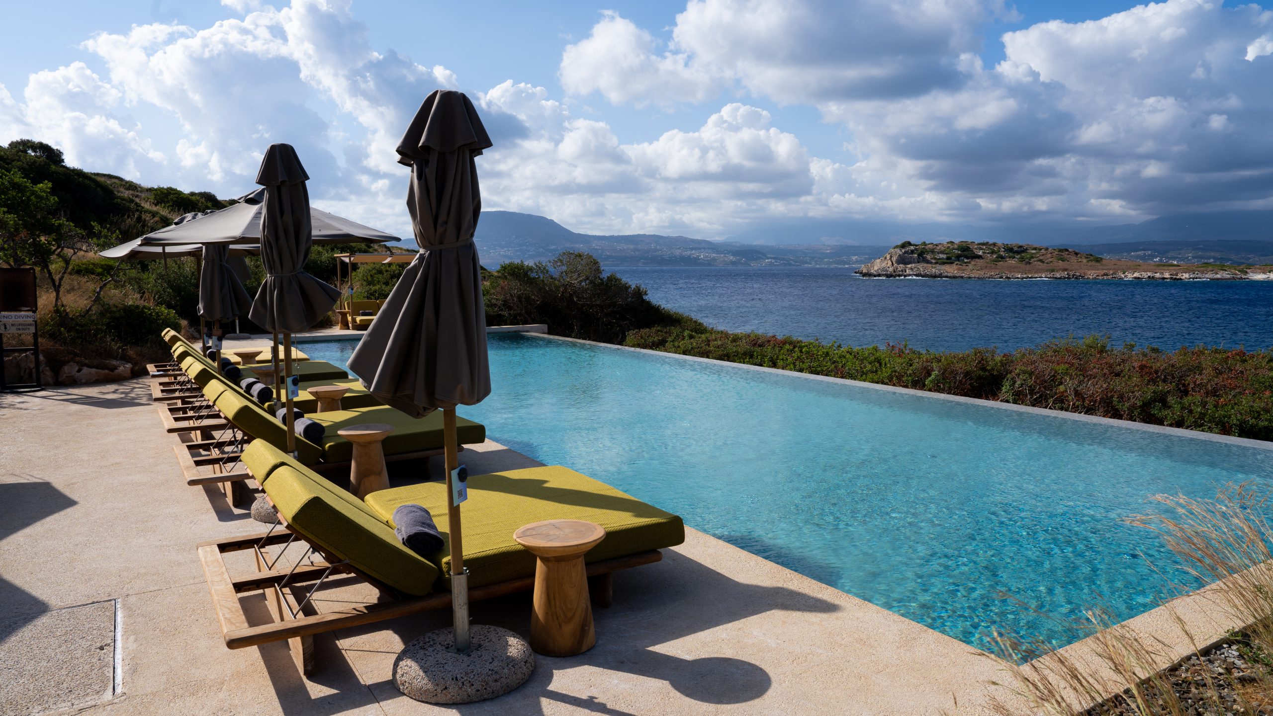 JW Marriott Crete Resort & Spa: The Complete Guide to Greece’s First JW Marriott 16 Adults-only infinity pool at JW Marriott Crete with yellow loungers and parasols, looking out over the bay toward the White Mountains