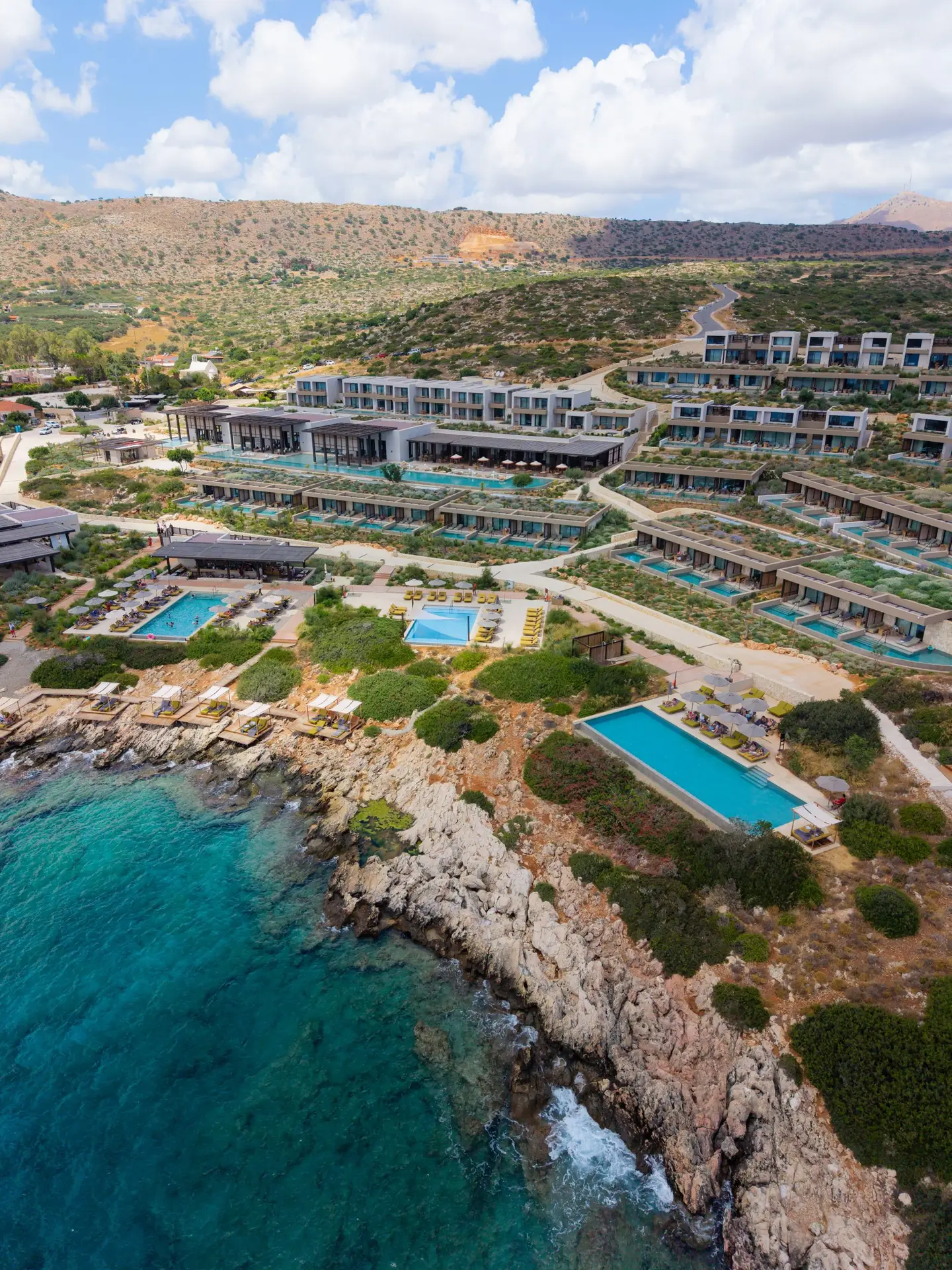 JW Marriott Crete Resort & Spa: The Complete Guide to Greece’s First JW Marriott 5 Aerial view of JW Marriott Crete showing the outdoor pools and rows of suites with private pools above the rocky coast