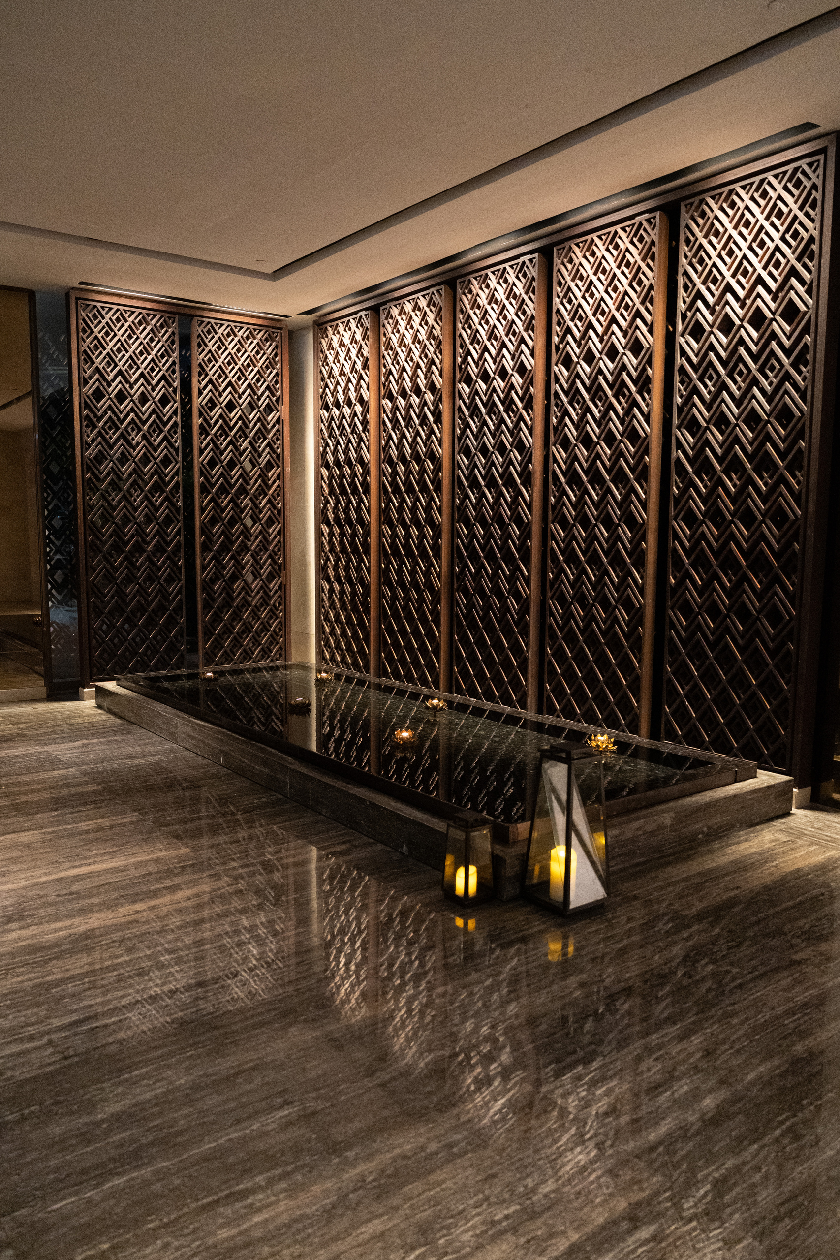 Wooden screens and still water lit by candles on the way to the Living Room, Capella Bangkok