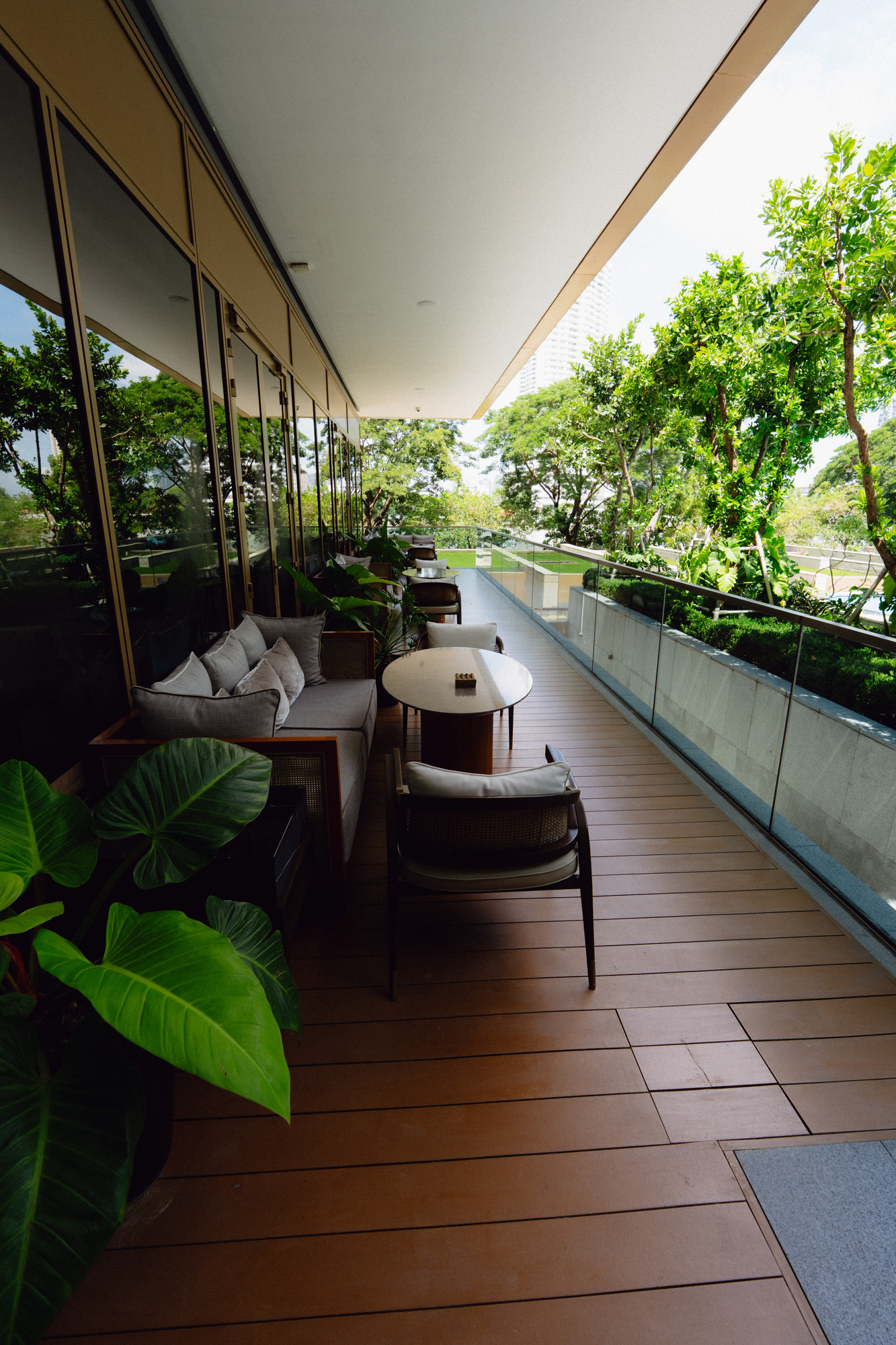 Shaded terrace with sofas and tropical plants above the pool at Capella Bangkok