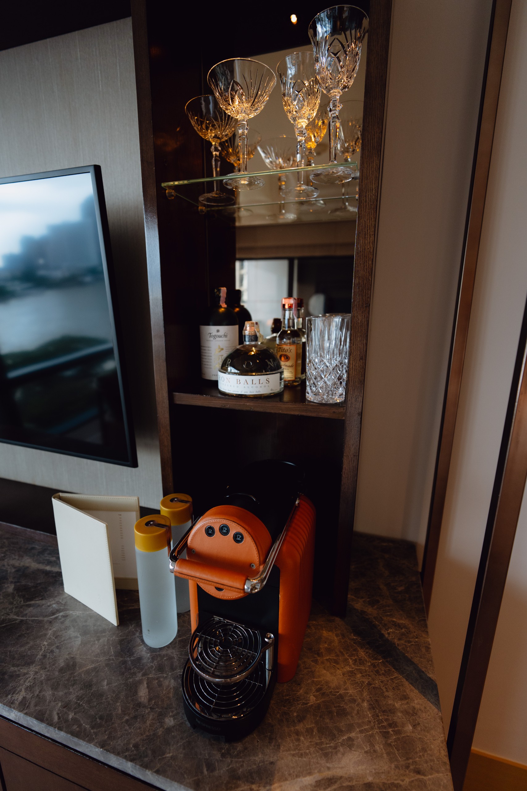 Minibar with crystal glasses and an espresso machine in a Riverfront Premier room at Capella Bangkok