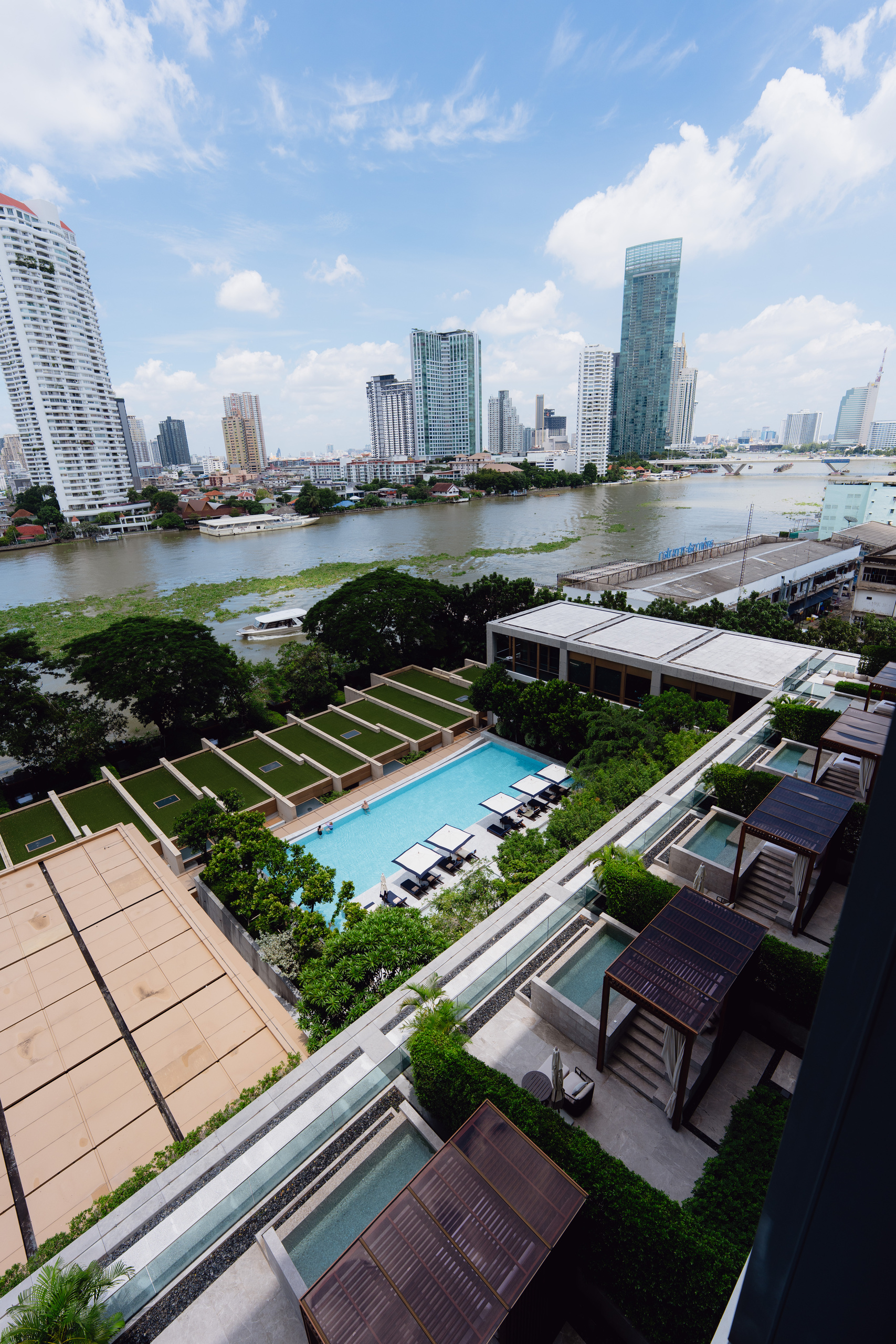 View over the pool, villa plunge pools and the Chao Phraya River from a Riverfront Premier balcony at Capella Bangkok