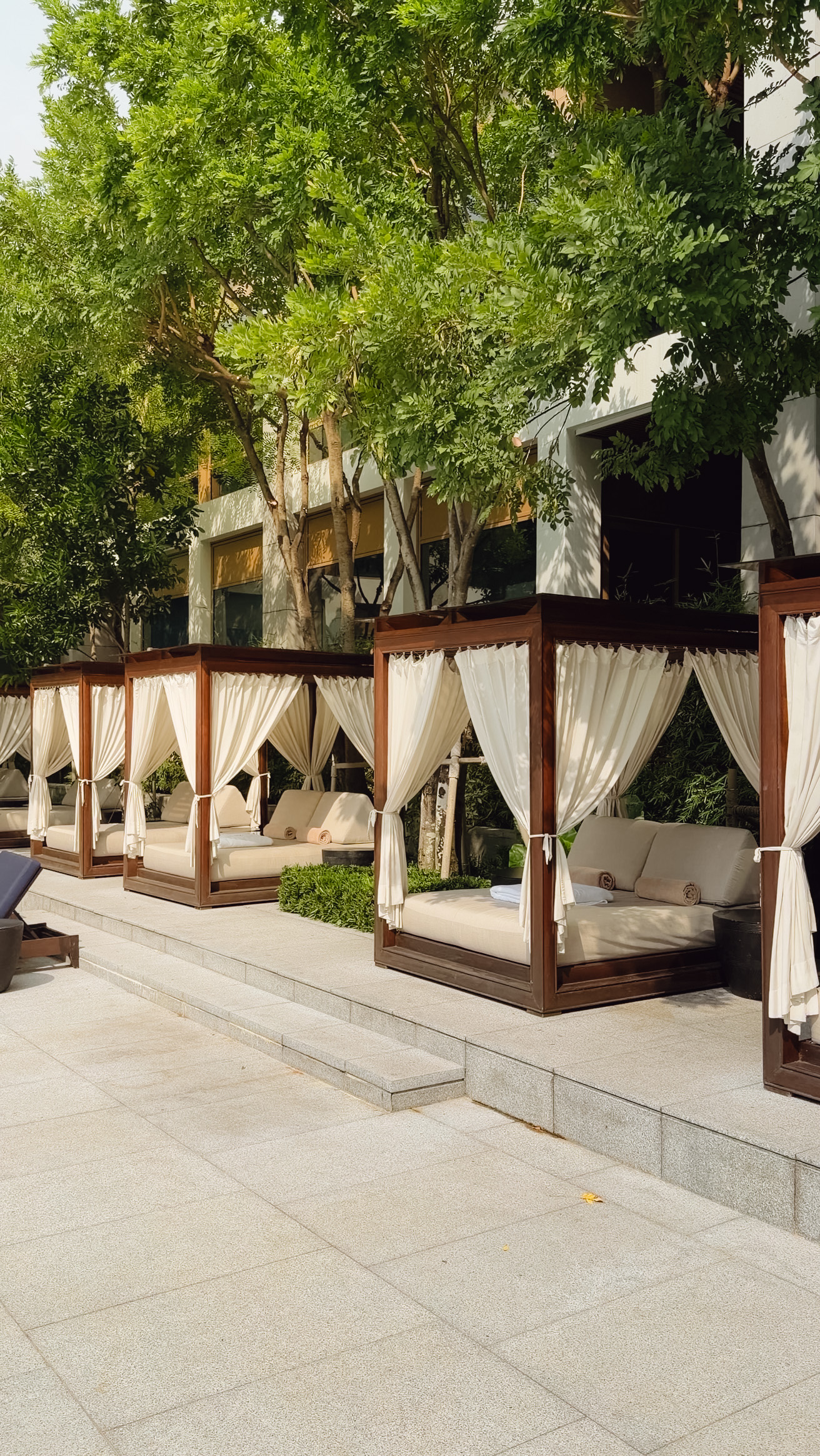 Poolside cabanas with white curtains at Capella Bangkok