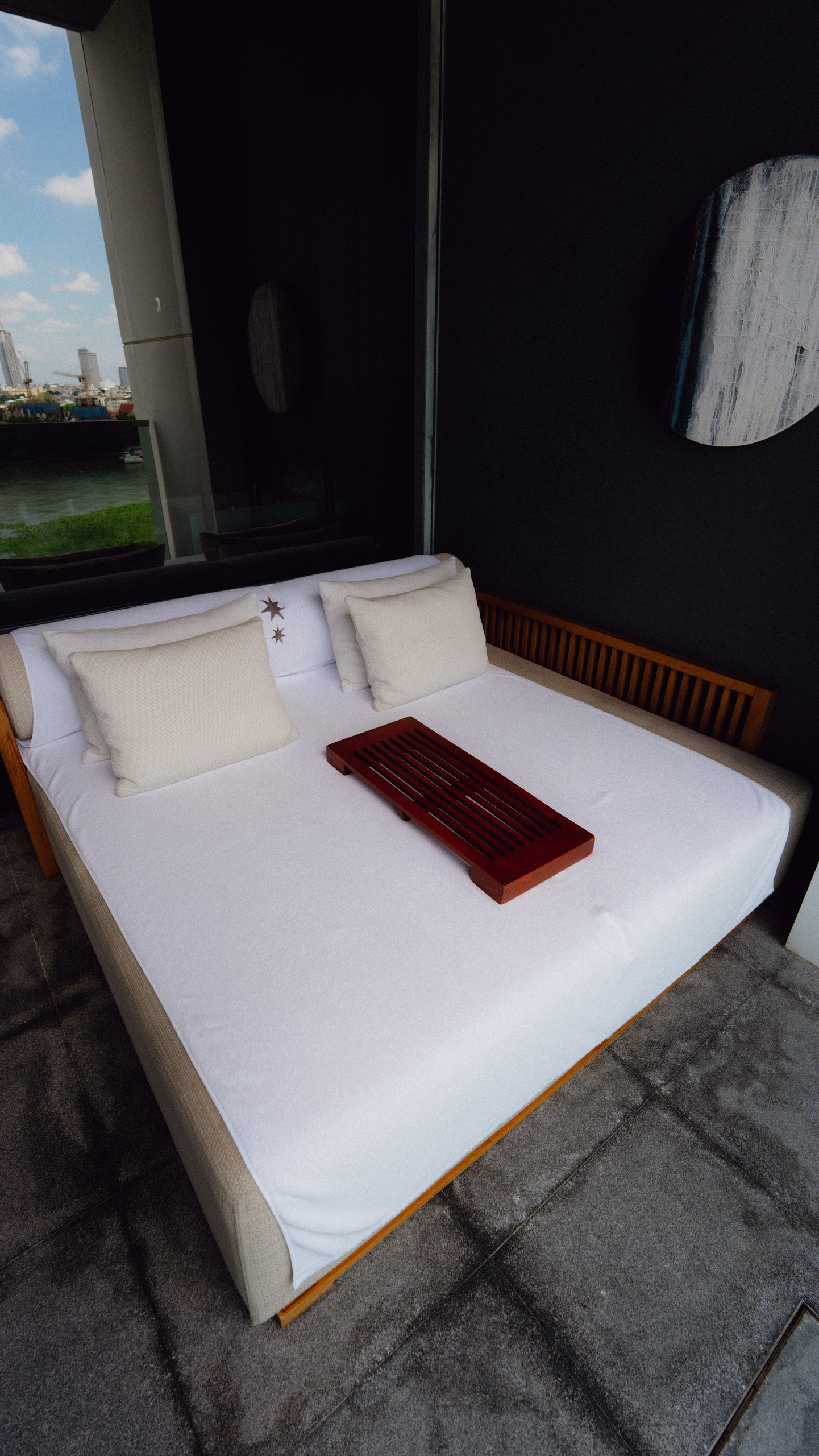 Daybed on the balcony of a Riverfront Premier room at Capella Bangkok with a view of the Chao Phraya River