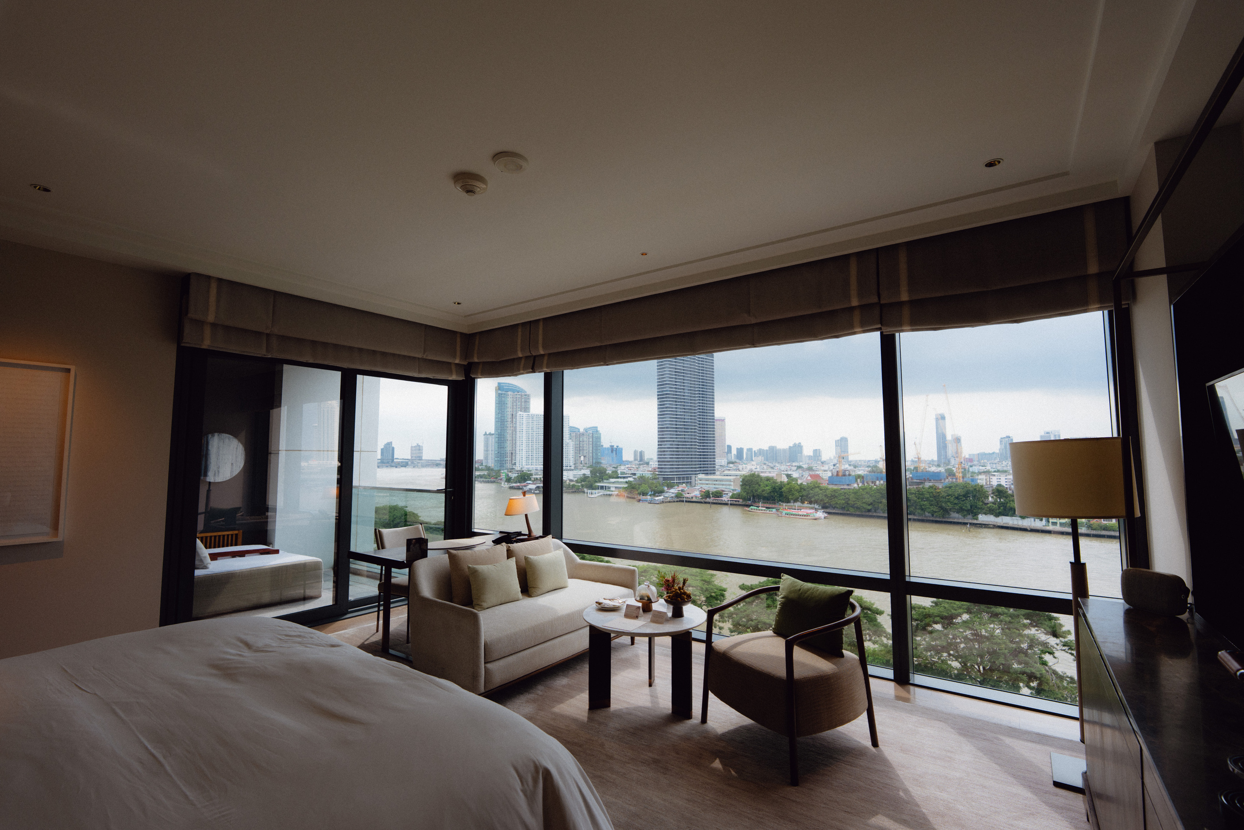 Riverfront Premier room at Capella Bangkok with a sofa and floor-to-ceiling windows facing the Chao Phraya River