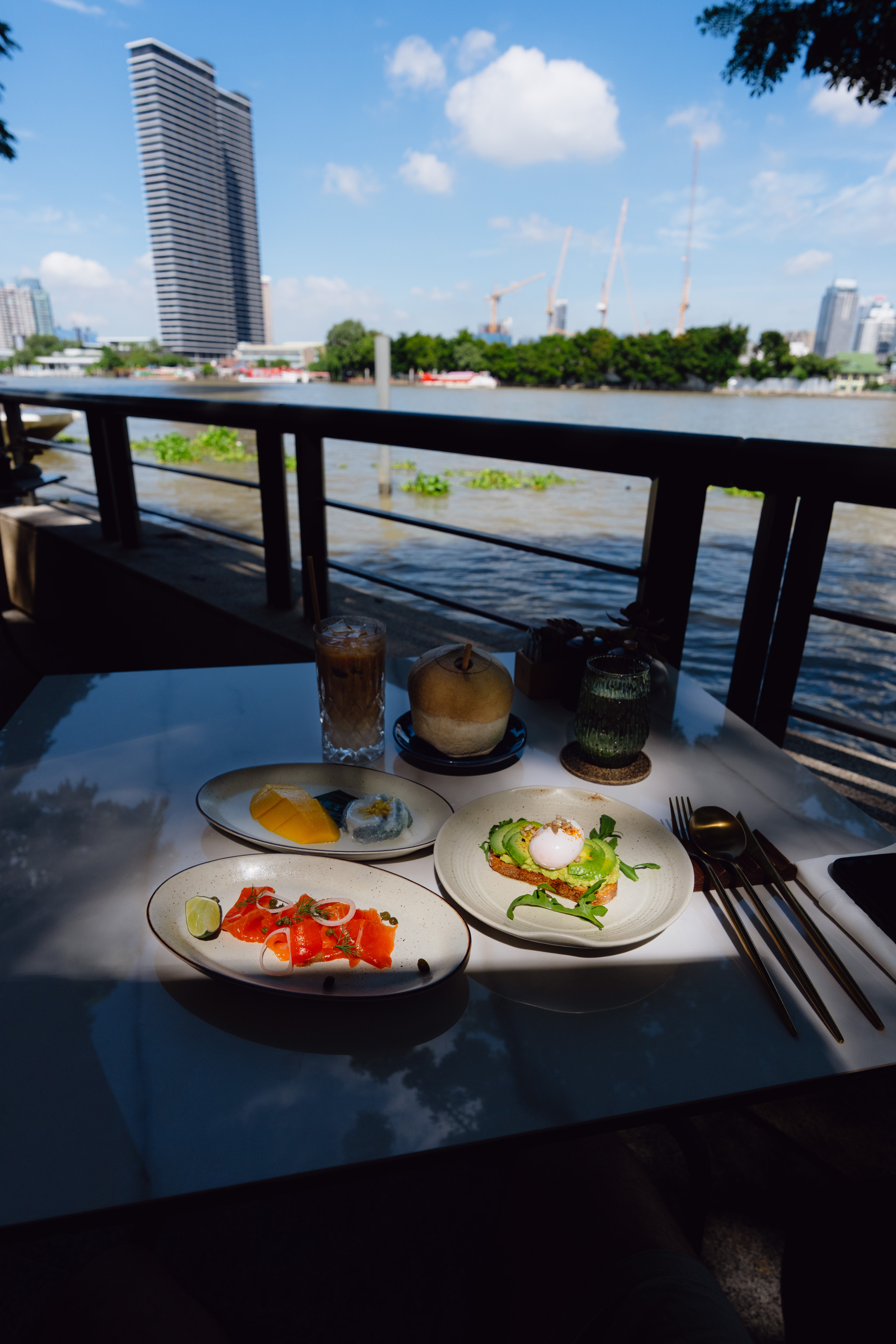 Avocado toast with poached egg, smoked salmon and mango sticky rice at a riverside breakfast table at Capella Bangkok