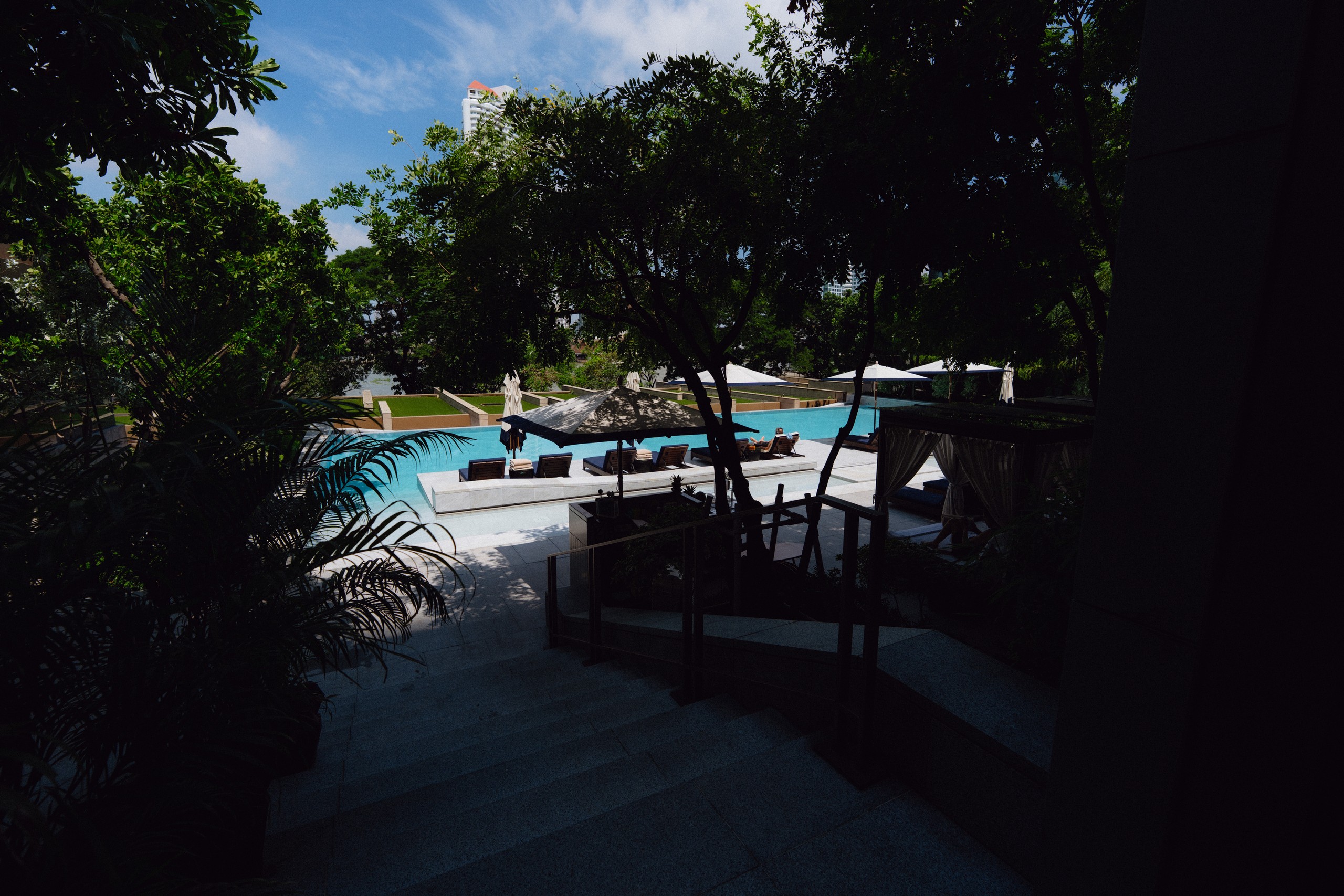 Steps leading down through tropical plants to the pool and cabanas at Capella Bangkok
