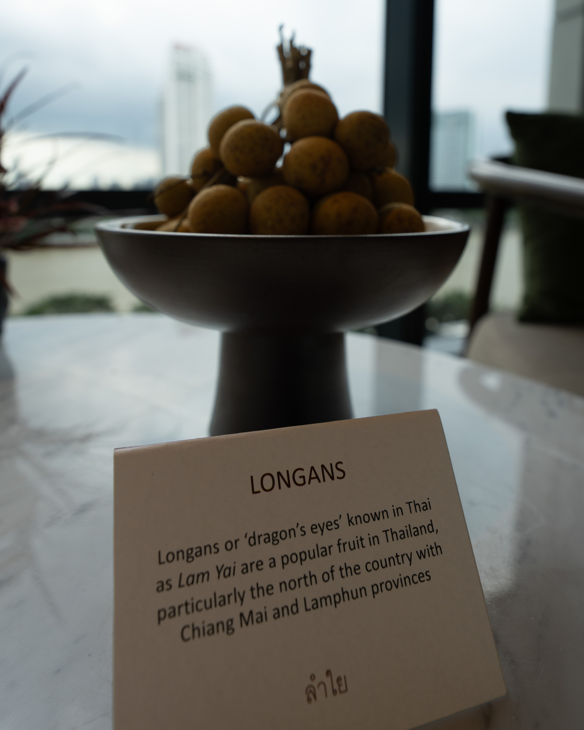 Bowl of longans with a card explaining the fruit on the marble table in a room at Capella Bangkok