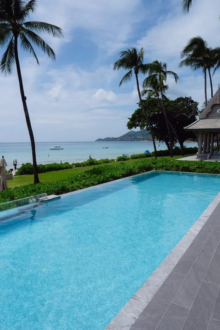 Centara Reserve Samui pool edged by palms with the sea beyond