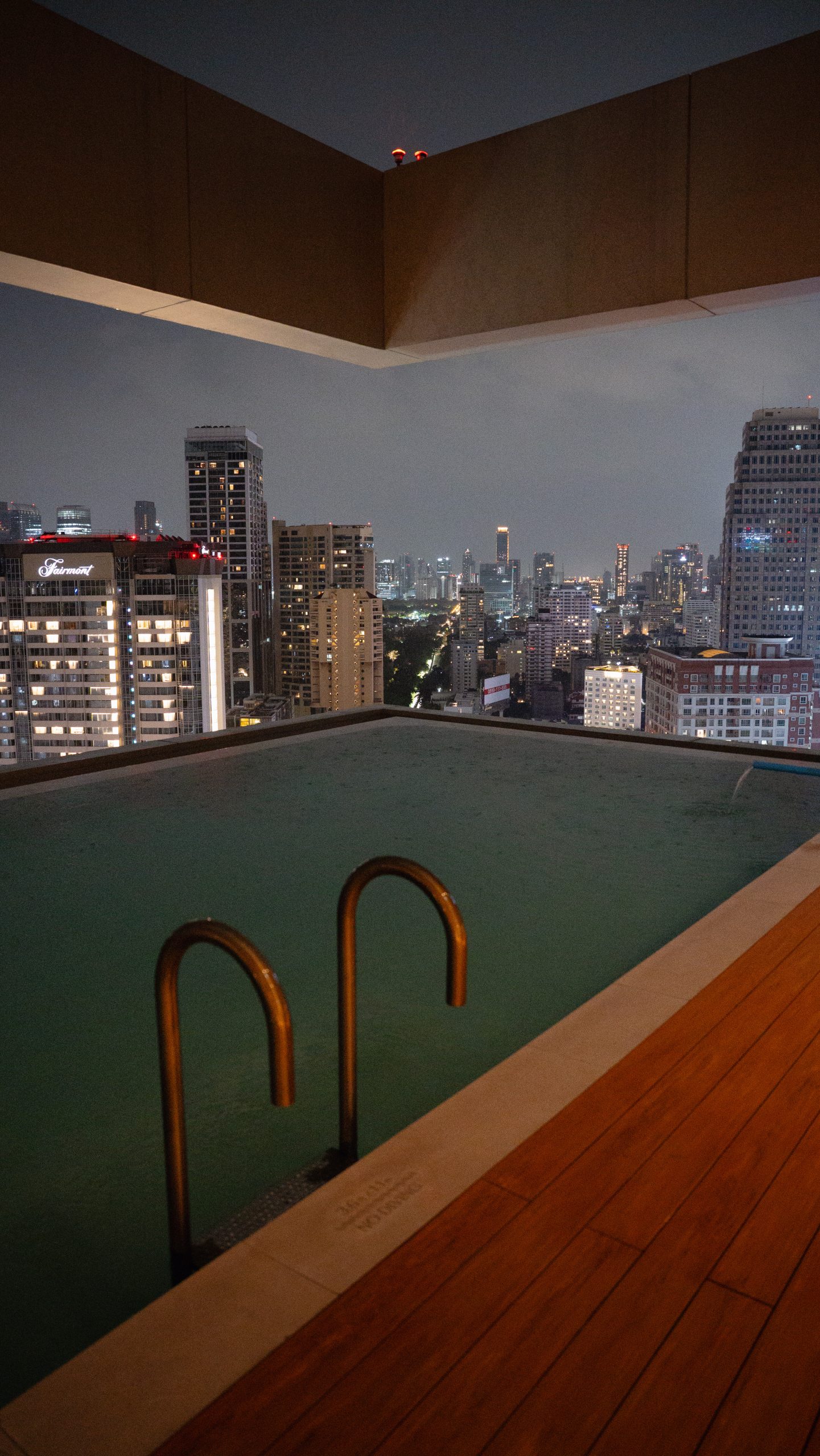 KROMO Bangkok rooftop pool at night overlooking the city skyline