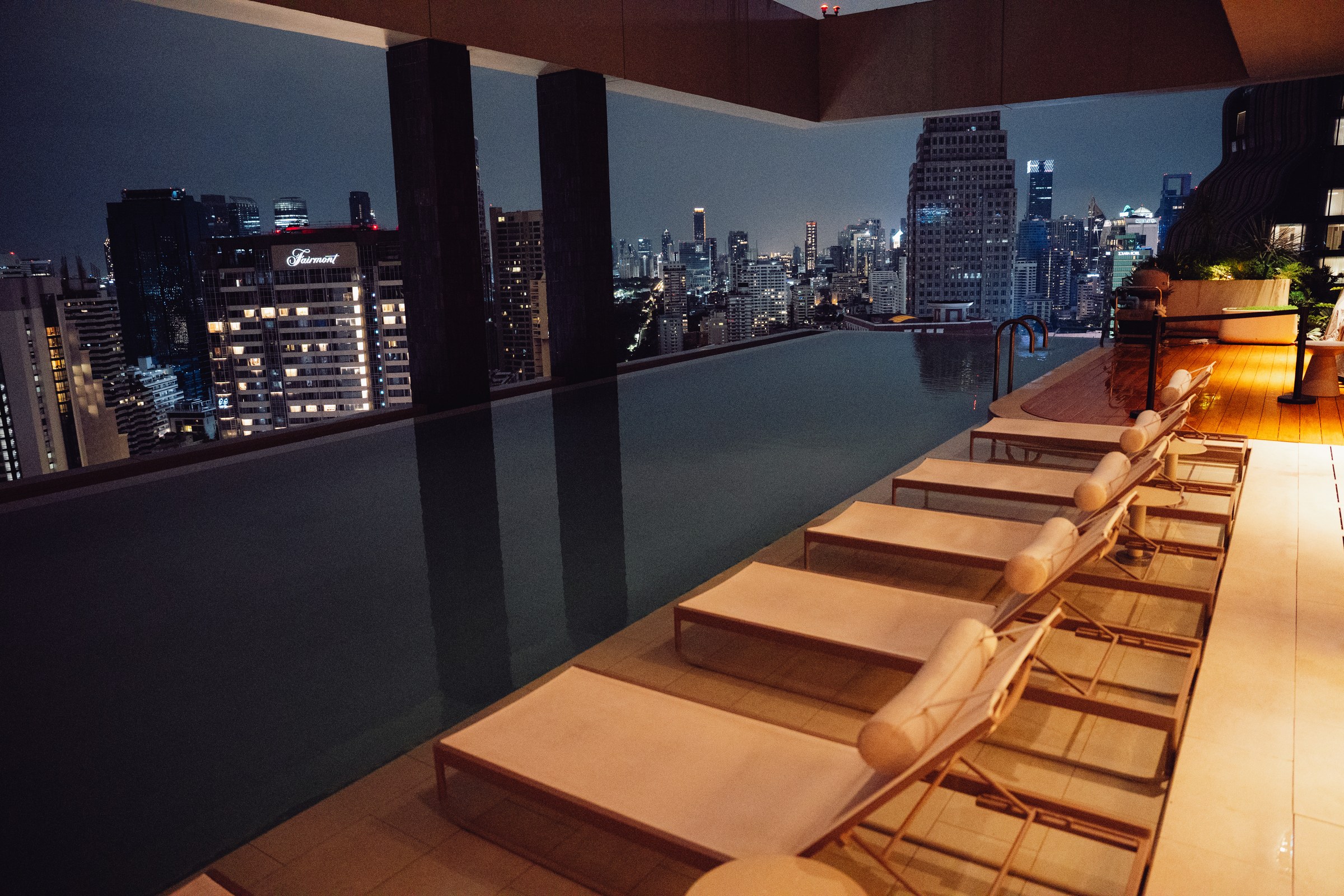 KROMO Bangkok rooftop pool at night with Bangkok skyline