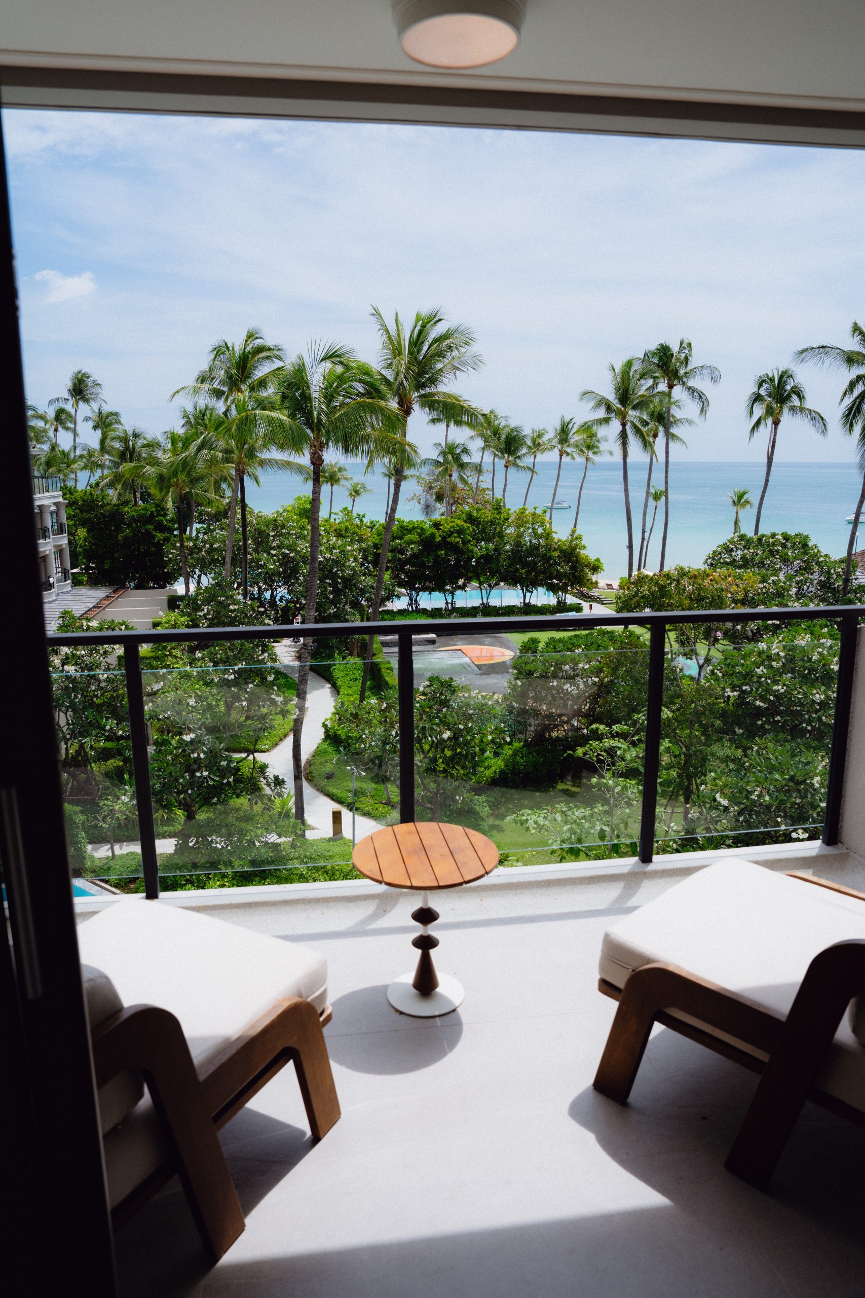 Luxury Ocean Suite balcony with two lounge chairs and a view over palms to the sea